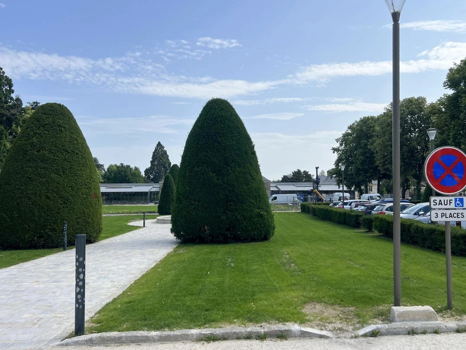 Espace vert urbain avec pelouse entretenue et topiaires coniques taillées