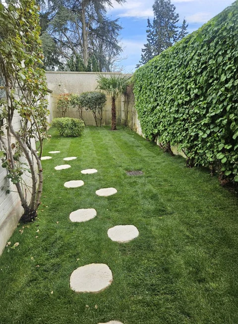 Jardin paysager résidentiel avec pelouse entretenue et allée de pas japonais en pierre naturelle