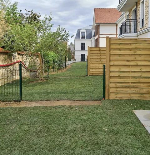 Jardin résidentiel avec pelouse fraîchement posée, clôture mixte bois et grillage rigide vert