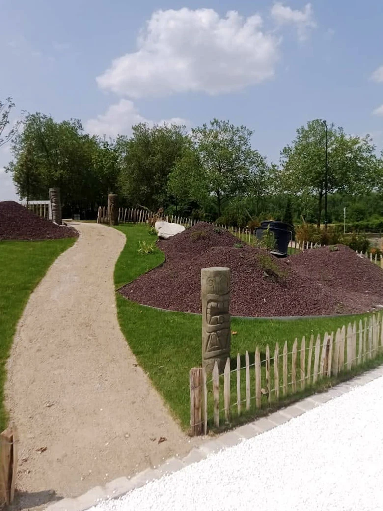Jardin japonais paysagé avec bassin d'eau verte au premier plan bordé de végétation ornementale et rochers décoratifs