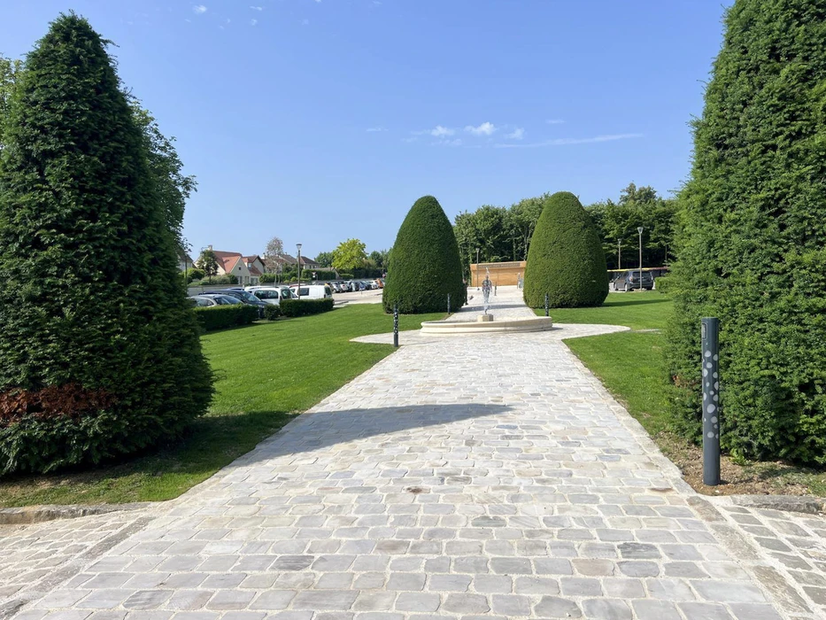 Jardin japonais paysagé avec bassin d'eau verte au premier plan bordé de végétation ornementale et rochers décoratifs