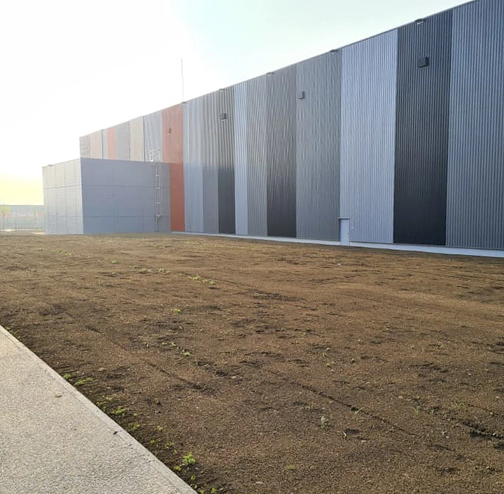 Aménagement paysager contemporain sur terrasse d'immeuble résidentiel avec jardinières cylindriques métalliques contenant palmiers et végétation méditerranéenne